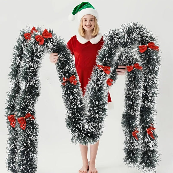 Guirlande de Noël enneigée avec nœuds rouges tenu par une femme.