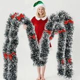 Guirlande de Noël enneigée avec nœuds rouges tenu par une femme.